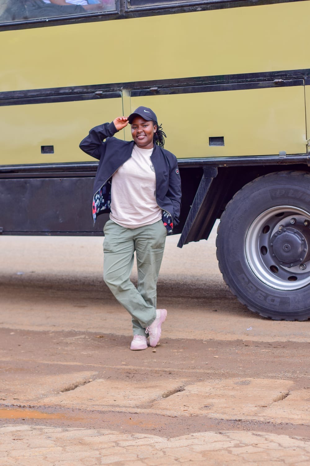 Monicah W. Kahora, safari guide at Binoman Africa Safaris, smiling in a cap in front of a safari vehicle