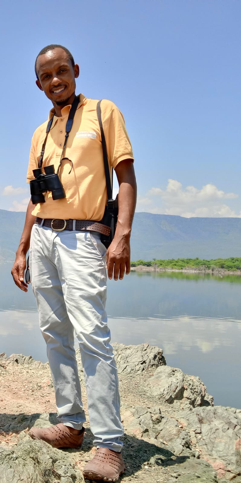 Stephen M. Leah, founder of Binoman Africa Safaris, with binoculars beside a lake